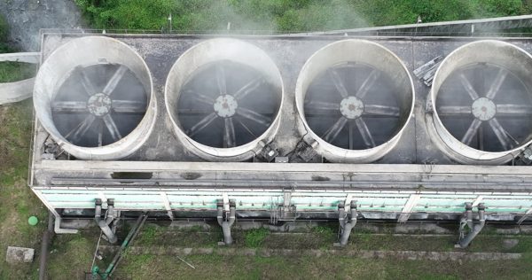 aerial drone shot of coal power plant with two high cooling towers next to blue river SBI 351517953