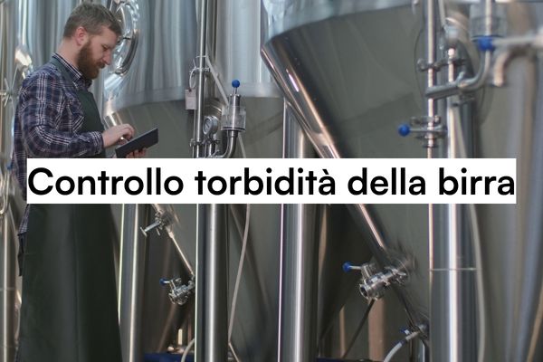 Perché il controllo torbidità della birra è essenziale in ogni birrificio? 7 Tecnico controlla la torbidità della birra su tablet in un birrificio industriale con serbatoi in acciaio inox